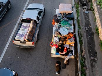 View from above as trucks loaded with personal items are waiting in traffic.