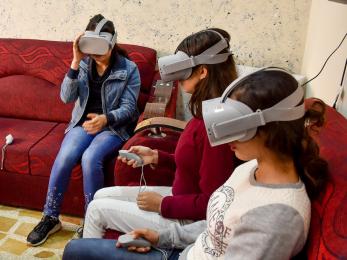 Young people sit on sofas while learning to use virtual reality equipment.