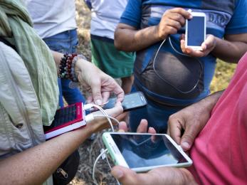 A group of people stand together and hold mobile devices.