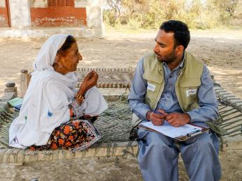 A mercy corps team member listening to a community member speaking.