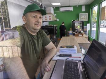 Ukrainian man stands at desk with laptop open.