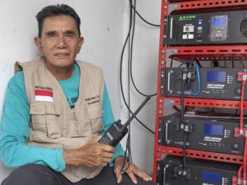 Indonesian man with hand radio and broadcasting equipment intended for use during emergency moments.