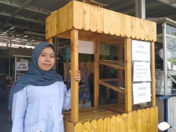 Nour aulia standing next to her food kiosk business.
