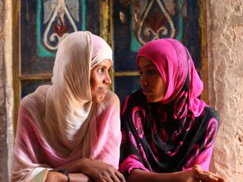 A mother and child sit together and look at each other.