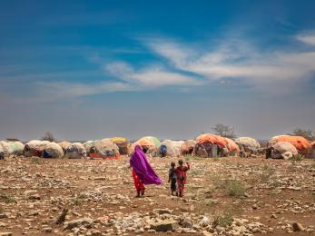 Two people walking towards temporary structures. 