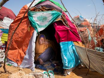  a woman peers out from her shelter in a camp for displaced people in the desert outside mogadishu, somalia. 