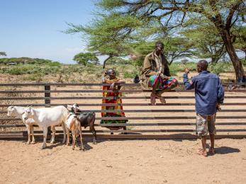 A person witting on a fence conversing with two other people. 