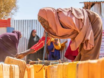 A person reaching for a jerry can at an internally displaced persons camp.