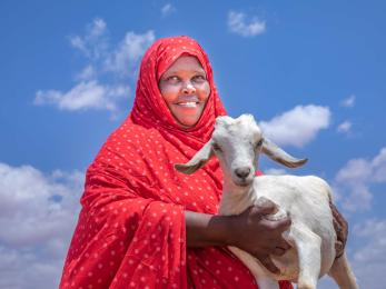 A pastoralist and livestock owner holding one of their goats.