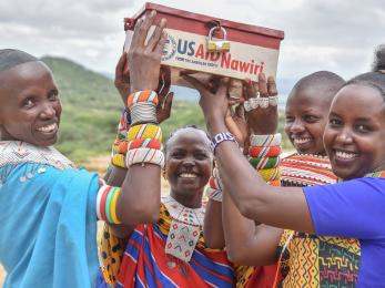 Four people holding up a locked box.