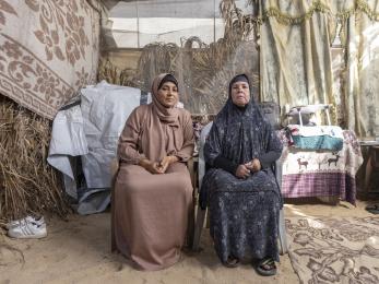 Two palestinian women sit outside their tent in gaza.
