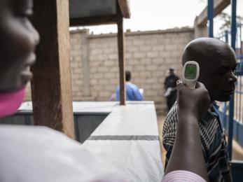 A health worker takes the temperature of an individual.